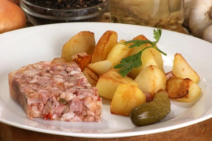 Teller mit Sülze und Bratkartoffeln