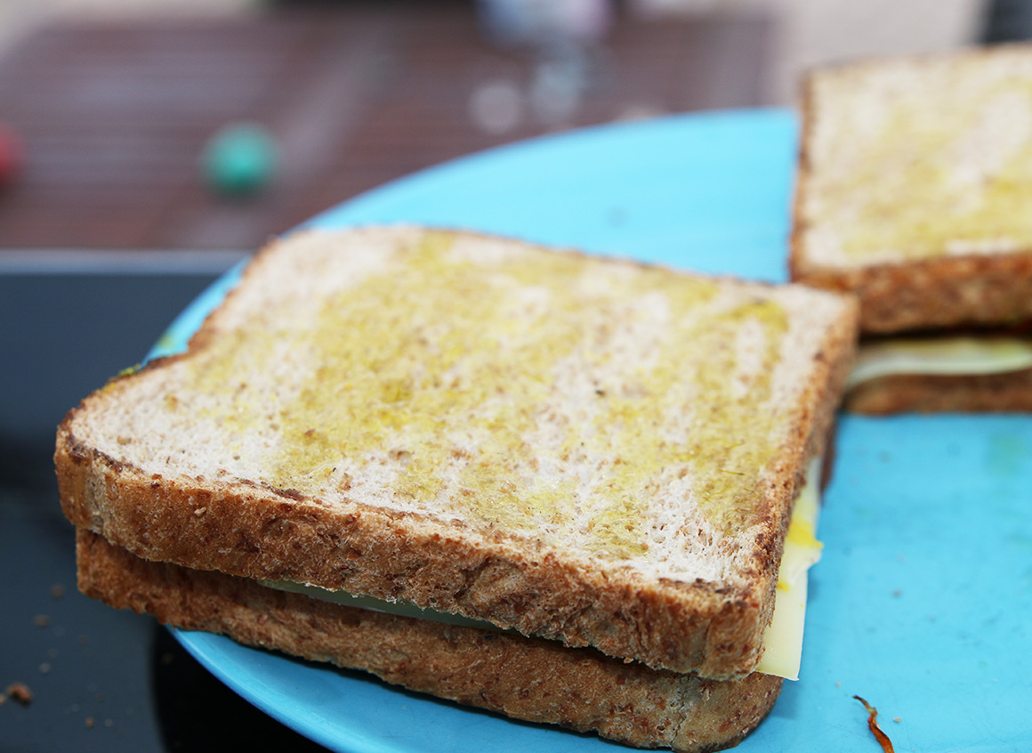 Toast mit einer weiteren Scheibe zuklappen und beidseitig mit Olivenöl einpinseln.