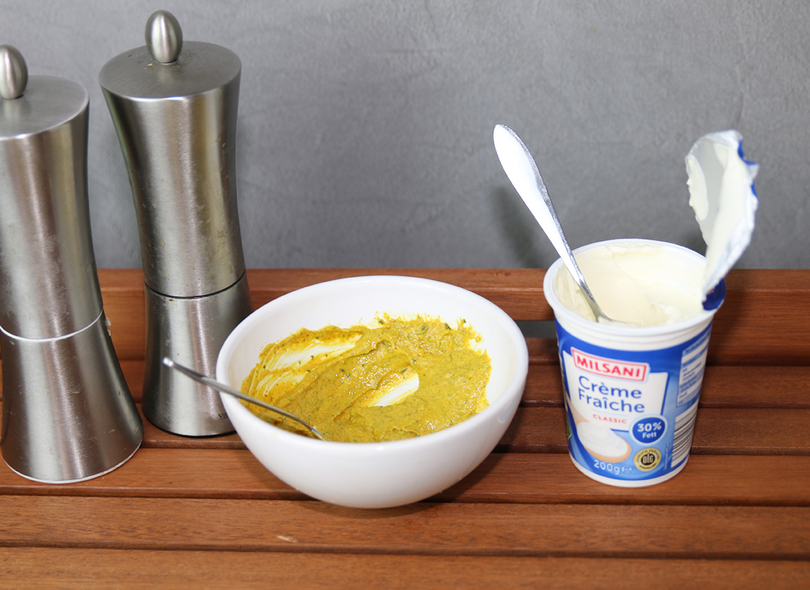 Die Olivenöl-Currypaste mit dem Creme Fraiche verrühren und nach Bedarf salzen und pfeffern.